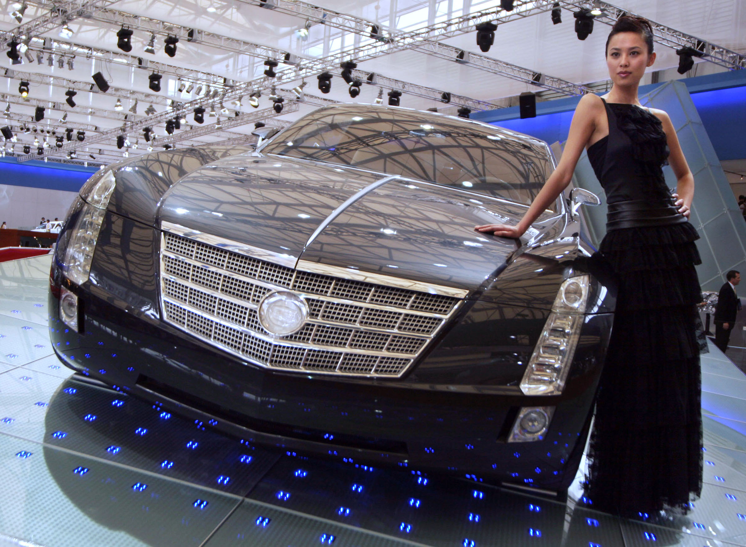 A Chinese model poses next to the Cadillac Sixteen concept vehicle at Auto 
